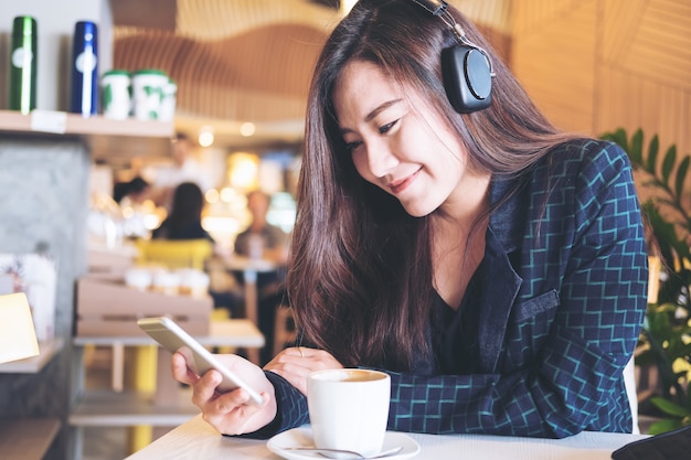 Asian woman listening to music with headphone and holding smart phone