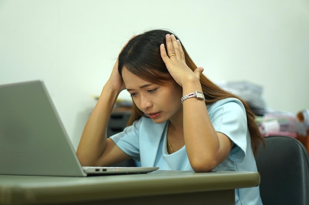 Asian woman looking at computer Frustrated by declining earnings