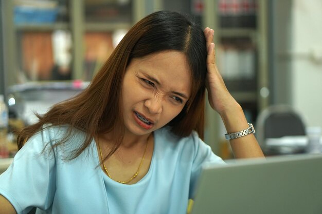 Asian woman looking at computer Frustrated by declining earnings