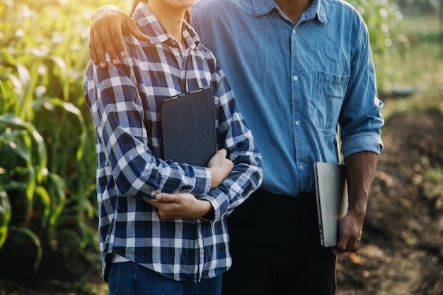 Asian woman and man farmer working together in organic hydroponic salad vegetable farm using tablet inspect quality of lettuce in greenhouse garden Smart farming