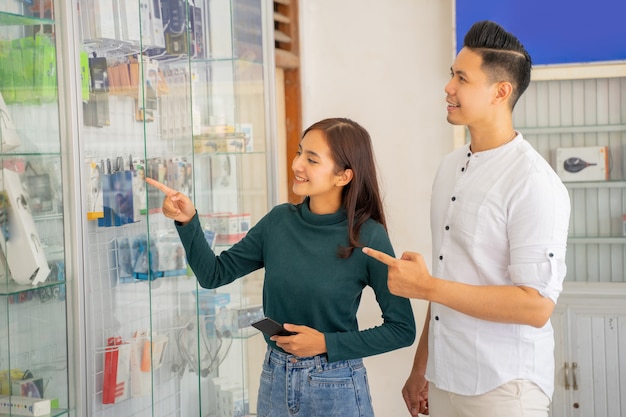 An asian woman and man standing pointing to a glass display case