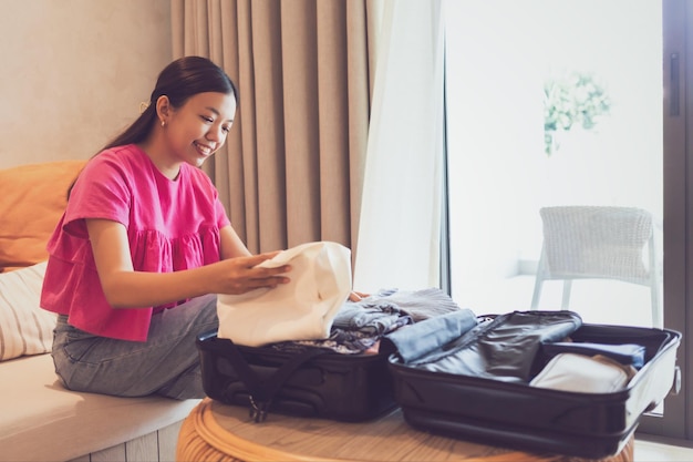 Asian woman packing bag for a trip at weekend vacationConcept of happy travel lifestyle