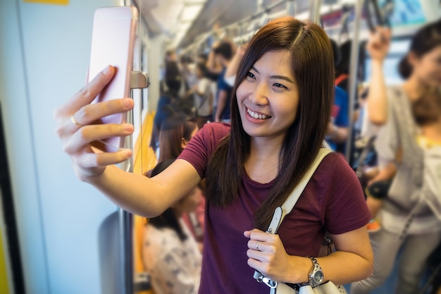 Asian woman passenger with casual suit taking selfie by mobile phone