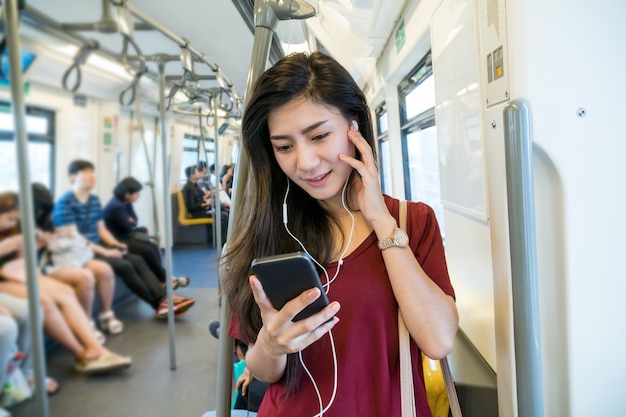 Asian woman passenger with casual suit using and listening the song