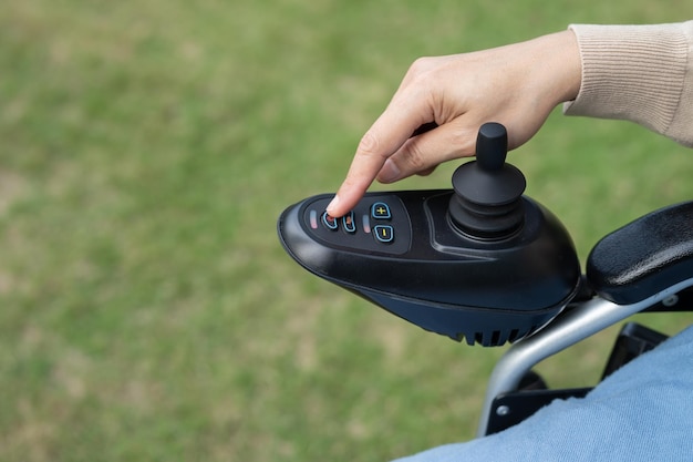 Asian woman patient on electric wheelchair with joystick control at hospital