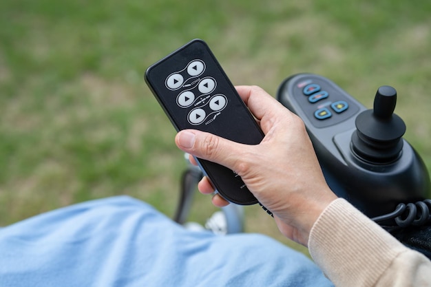 Asian woman patient on electric wheelchair with remote control at hospital