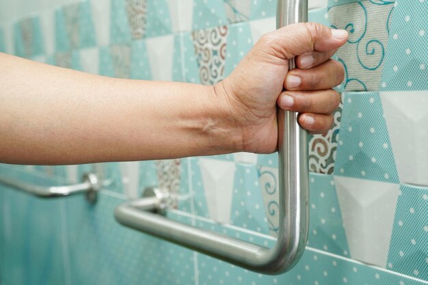 Asian woman patient use toilet support rail in bathroom handrail safety grab bar security in nursing hospital