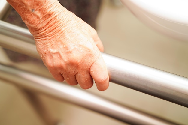 Asian woman patient use toilet support rail in bathroom handrail safety grab bar security in nursing hospital