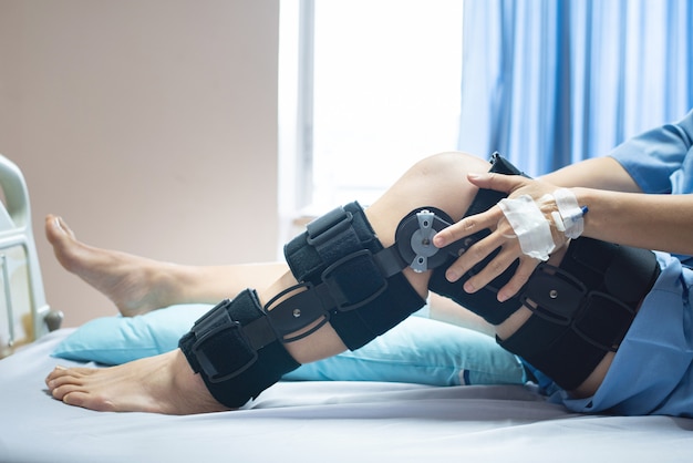 Asian woman patient with bandage compression knee brace support injury on the bed in nursing hospital.healthcare and medical support.