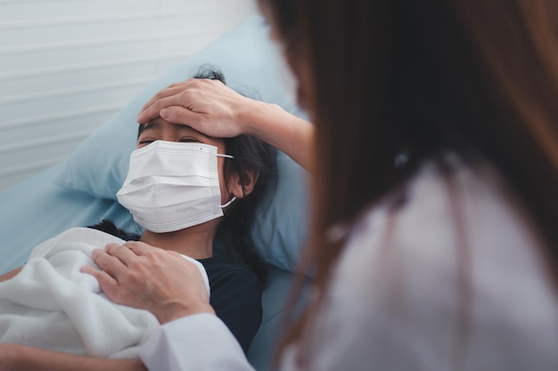 Asian woman pediatrician doctor put hand on chest for exam a little girl patient and heck heart