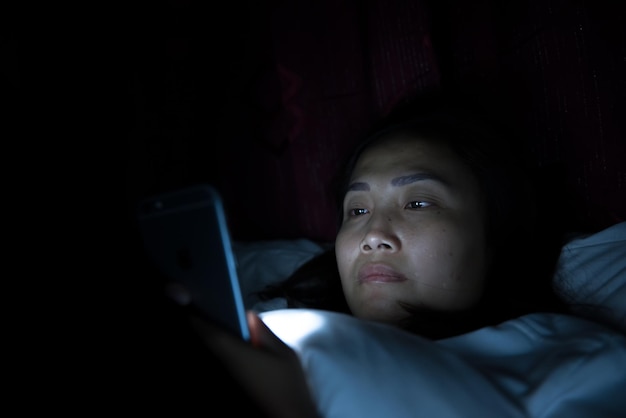 Asian woman play smartphone in the bed at nightThailand people