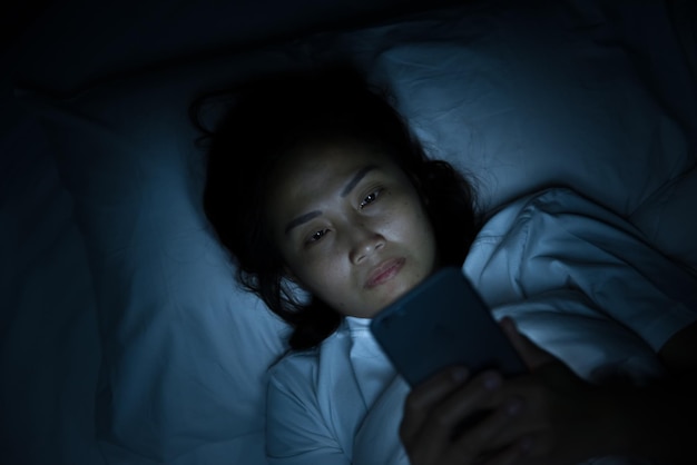 Asian woman play smartphone in the bed at nightThailand people