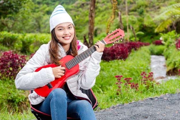 Asian woman playing guitar enjoying camp activity