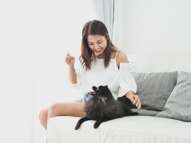 Asian woman playing with little dog black color in living room lifestyle girl with pet