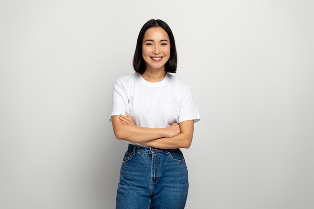 Asian woman posing arms crossed looking at camera with charming smile