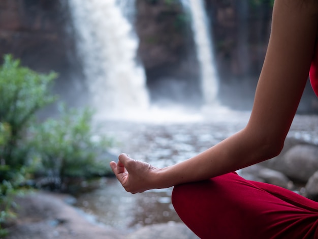 Asian woman practicing or doing yoga at the waterfall