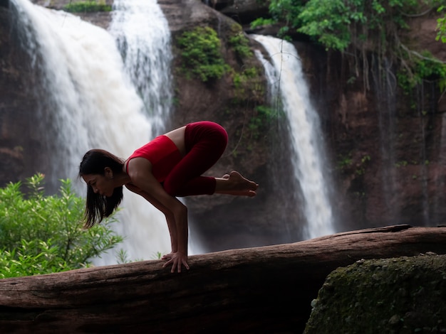 Asian woman practicing or doing yoga at the waterfall