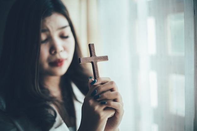 Asian woman praying with wood cross and believe in God.