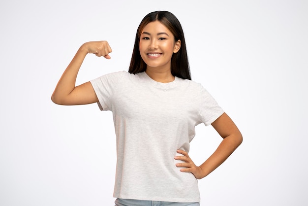 Asian woman raising arms showing biceps as metaphor of female power