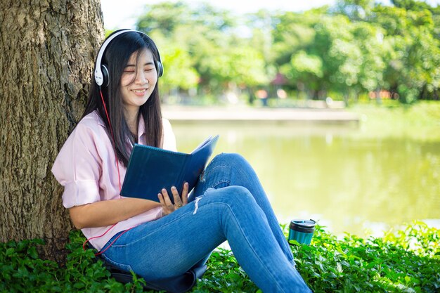 Asian woman reading a book and smiling in the parkSatisfied asian woman reading a book in a park