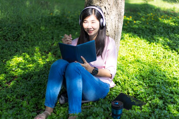 Asian woman reading a book and smiling in the parkSatisfied asian woman reading a book in a park