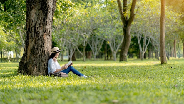 Asian woman relax by sitting happily reading a book in the park