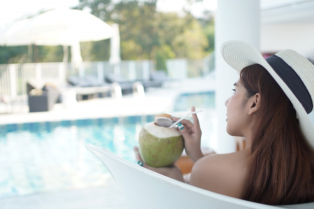 Asian woman Relax at the swimming pool of a luxury resort.