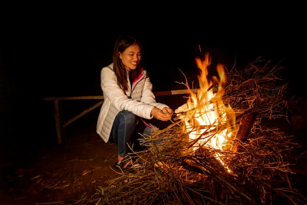 Asian woman roasting marshmallow on campfire