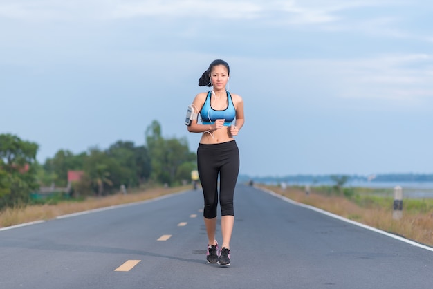 Asian woman running on road in park