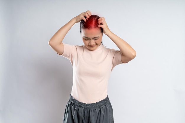 Asian woman scratching her head with red spot standing isolated on white background