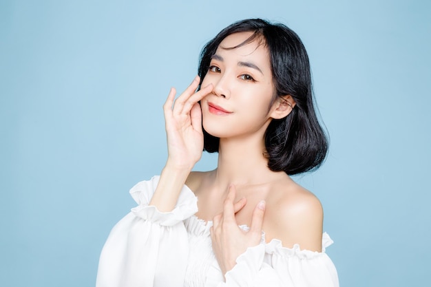 Asian woman short hair with Perfect clean fresh skin Cute female model with natural makeup and sparkling eyes on blue isolated background Facial treatment Cosmetology beauty Concept