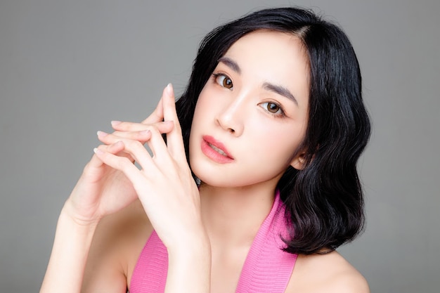 Asian woman short hair with Perfect clean fresh skin Cute female model with natural makeup and sparkling eyes on grey isolated background Facial treatment Cosmetology beauty Concept