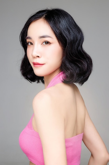 Asian woman short hair with Perfect clean fresh skin Cute female model with natural makeup and sparkling eyes on grey isolated background Facial treatment Cosmetology beauty Concept