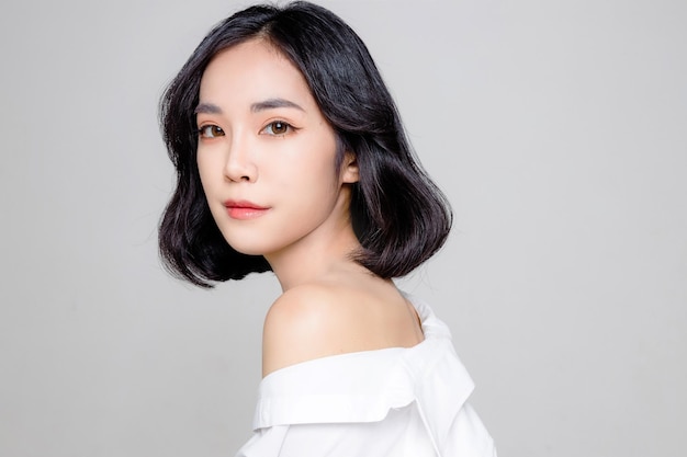 Asian woman short hair with Perfect clean fresh skin Cute female model with natural makeup and sparkling eyes on white isolated background Facial treatment Cosmetology beauty Concept