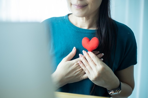 Asian Woman showing red heart on computer Dating Online concept