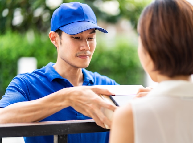 Asian woman sign electronic signature to portable mobile device after receive package