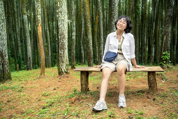 Asian woman sitting on the bench in the forest