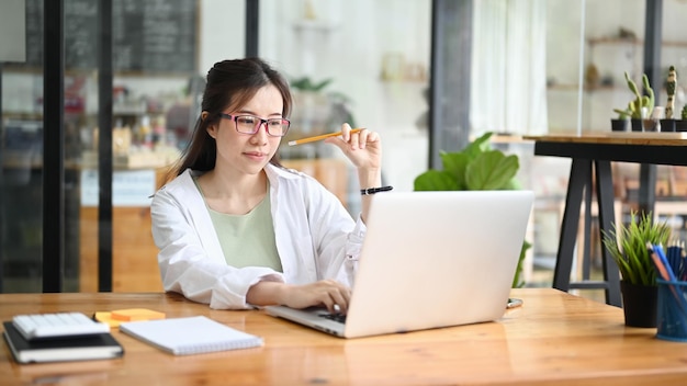 Asian woman sitting in coffee shop and using laptop computer