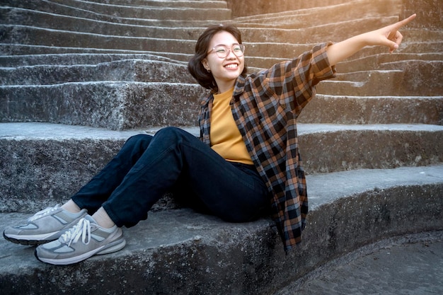 Asian woman sitting on the stone steps while pointing to something