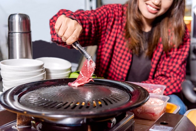 Asian woman sitting while grilling barbeque enjoying camp activity