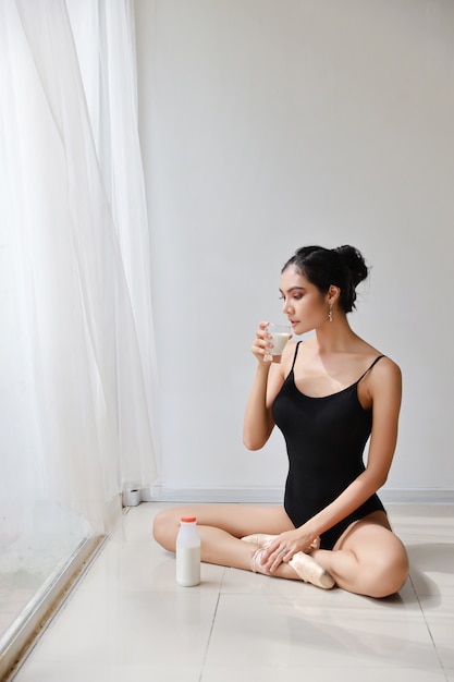 asian woman in sportswear with a glass of milk with white background in studio house