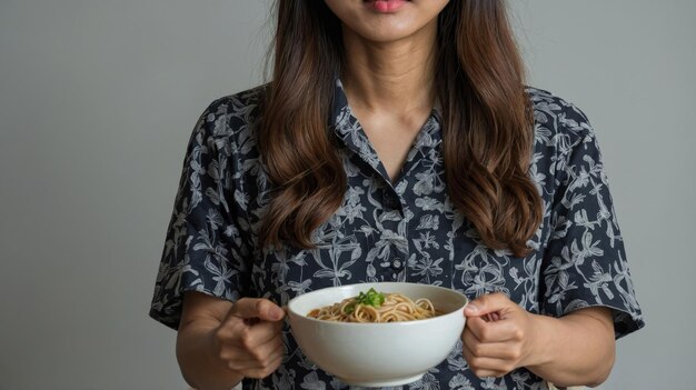 Asian woman standing holding a bowl of noodle giving