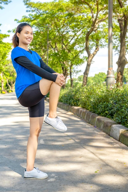 Asian woman stretching her legs before running