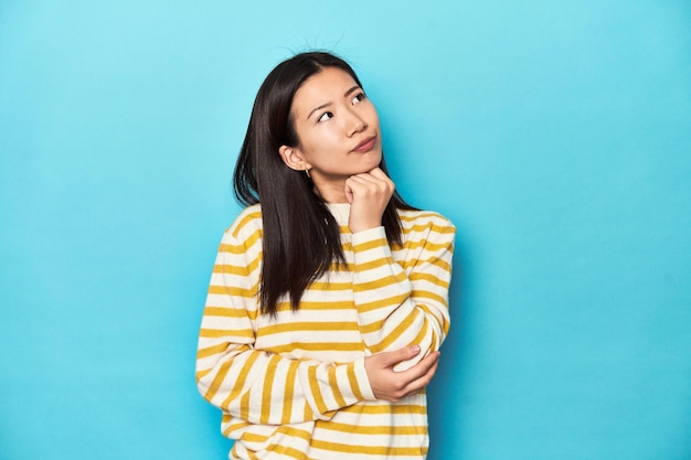 Photo asian woman in striped yellow sweater thinking and looking up being reflective