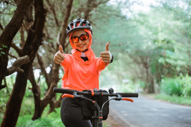 Asian woman in sunglasses with thumbs up while cycling