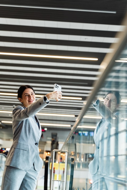 Photo asian woman taking selfie in airport terminal travel blogger taking selfie while waiting for boarding