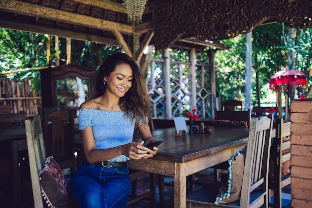 Asian woman texting sitting on chair on veranda