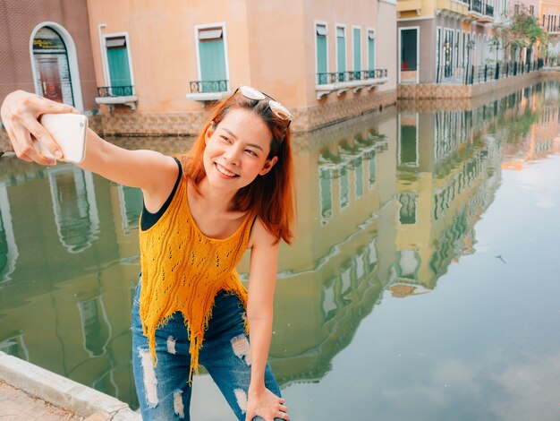 Asian woman tourist is taking selfie photo from the smartphone.