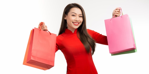 Asian woman in traditional vietnamese dress ao dai carrying paper shopping bags as a customer for lunar New Year festival celebration time happy feeling joyful