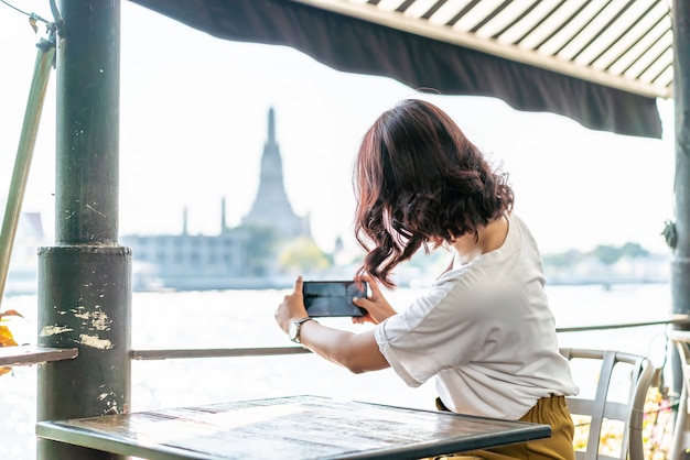 Asian woman traveler taking a photo in cafe